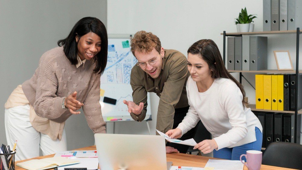 diverse-team-collaborating-on-project-around-laptop-in-modern-office