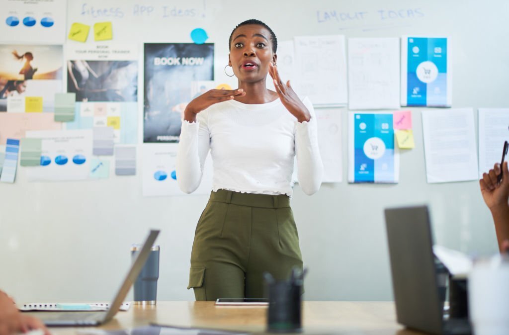 woman-presenting-and-speaking-in-front-of-a-whiteboard-in-a-meeting-room