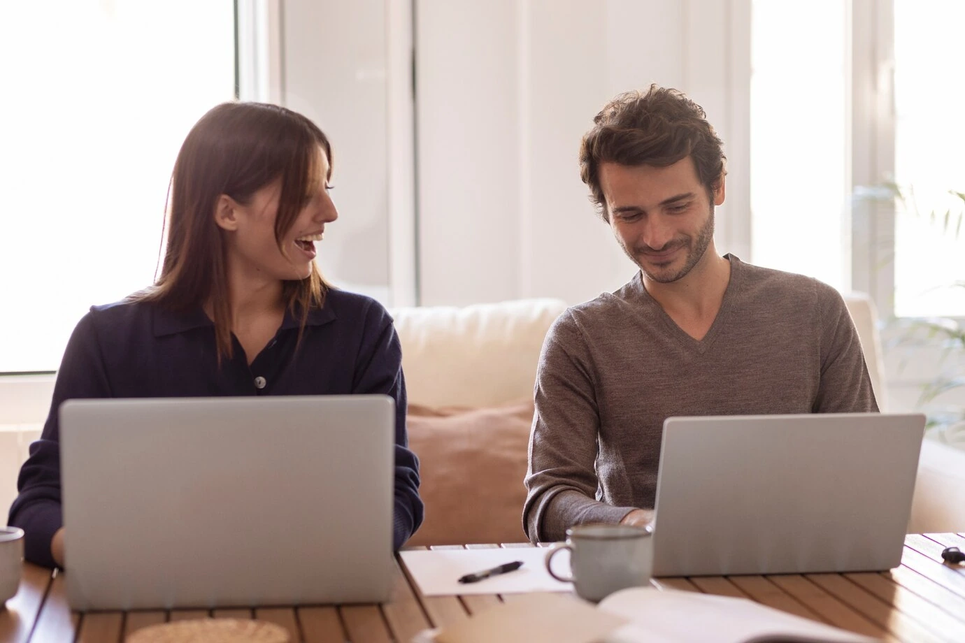 man-and-woman-working-on-laptops-smiling-in-casual-home-setting