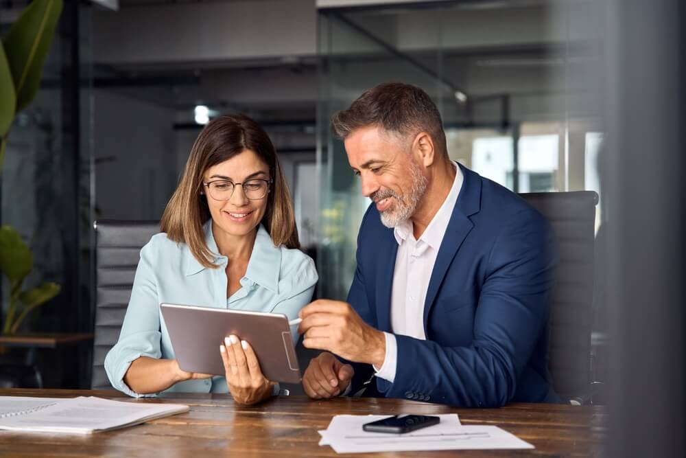 man-and-woman-smiling-and-discussing-on-a-tablet-in-an-office-setting