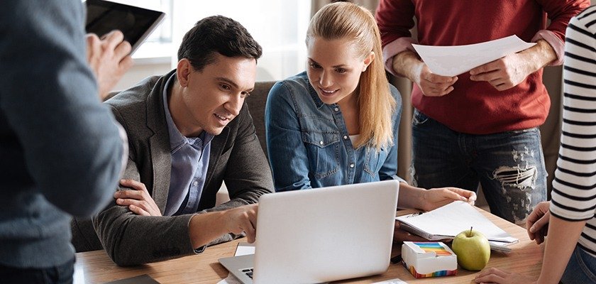 team-collaborating-around-laptop-in-modern-workspace