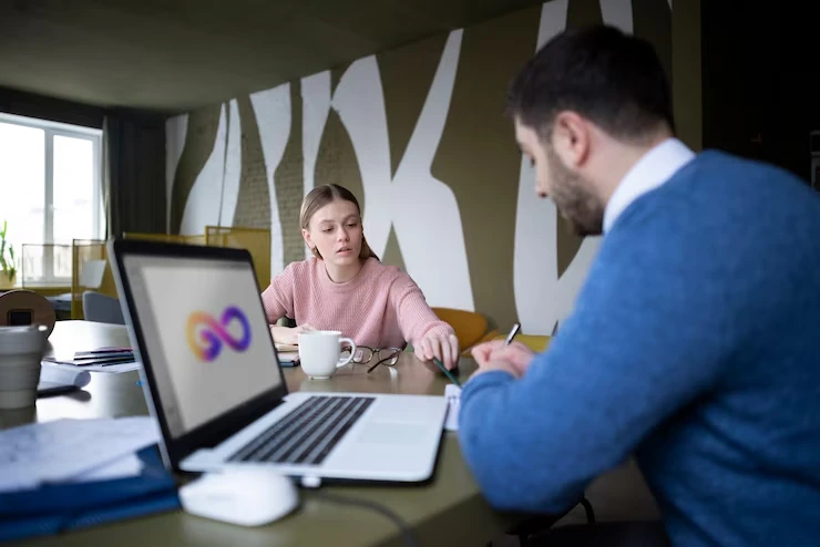 Two people collaborating with a laptop in a modern office.