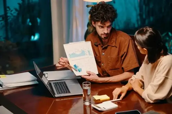 Two professionals in Regina discussing business analytics while reviewing charts and graphs during a strategy meeting