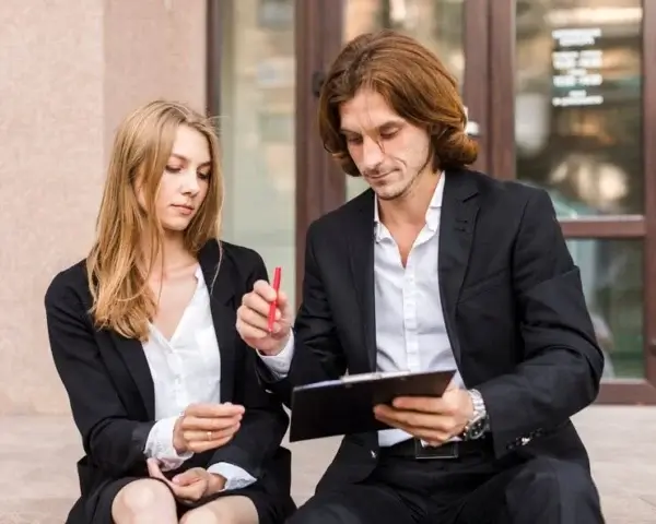 Two business professionals in Regina reviewing a document together while sitting outside an office building