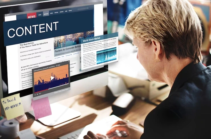 A professional working on a computer screen filled with articles and digital content, representing content optimization services in Canada.