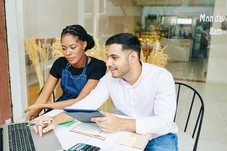 Two team members collaborating on a laptop, representing the Pearl Lemon schema markup service team working on client strategies.